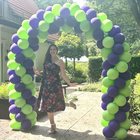 Marieke under a balloon arch at her goodbye party